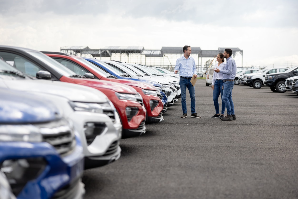 Salesman showing cars to a couple at the dealership valor venal del coche que es